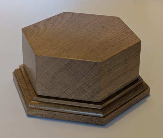 Solid Oak Hexagonal Trophy Base 122mm across flats and 50mm high This Hexagonal solid oak trophy base is 122mm across flats with flat verticle side of 50mm high and 70mm wide. The verticle side are ideal for engraving plates The overall height of the base is 73mm and green baize is on the underside.